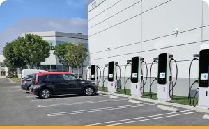 En rad moderna laddboxar installerade vid en kontorsfastighet med en elbil parkerad.